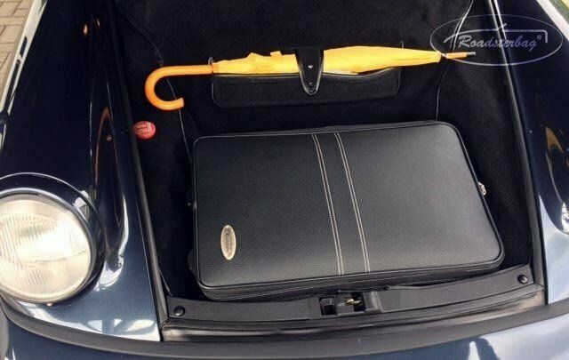 De kofferbak van een auto met daarin een koffer en een paraplu