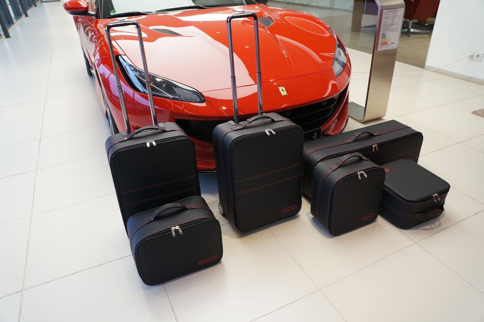 Een rode sportwagen staat geparkeerd naast een stapel bagage