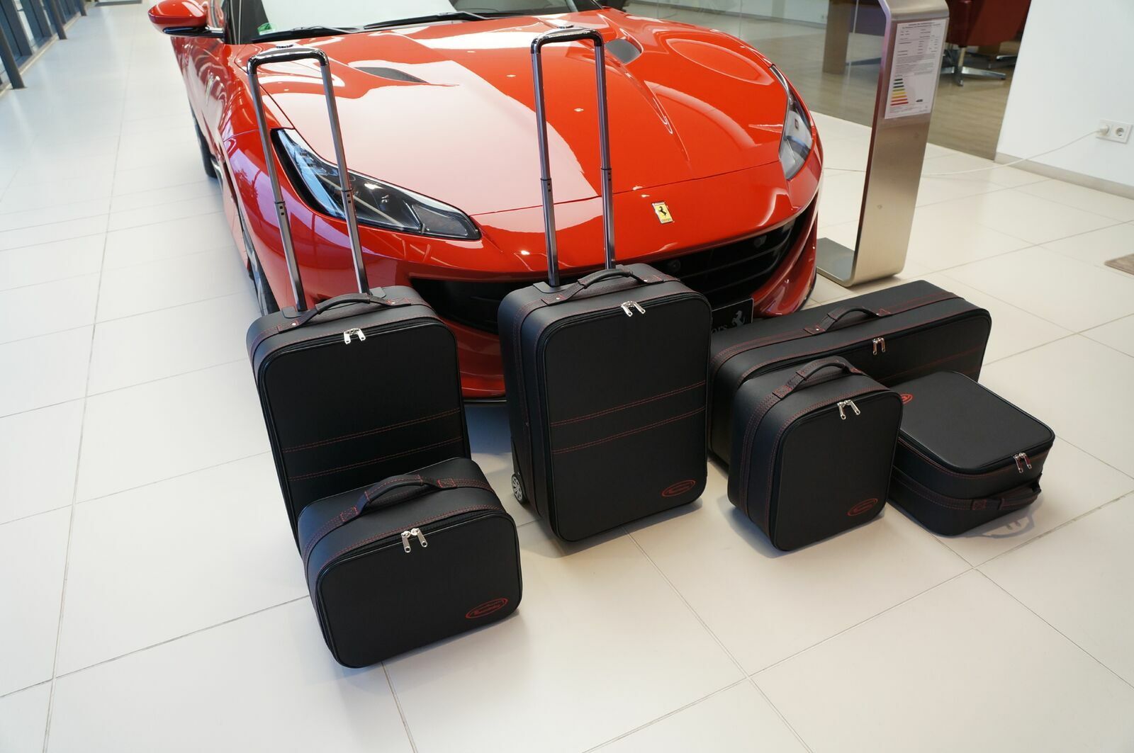 Een rode sportwagen staat geparkeerd naast een stapel bagage