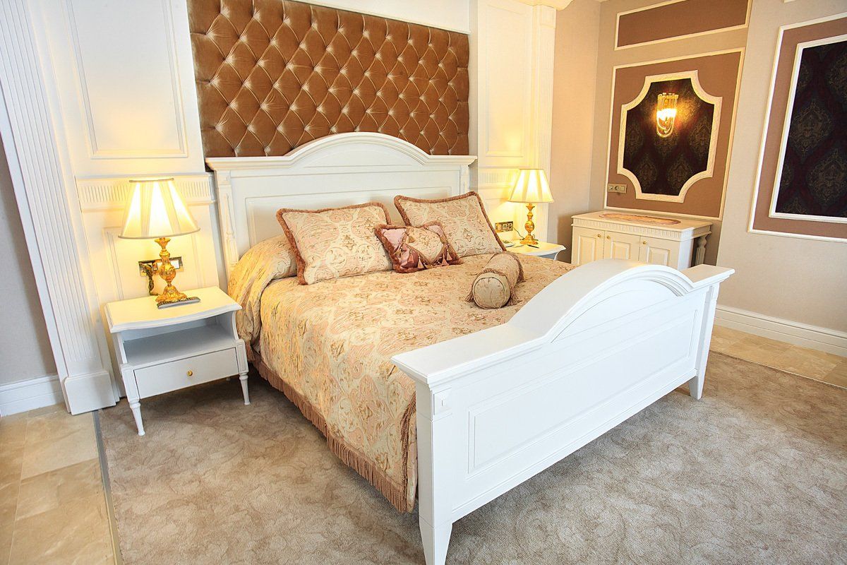 A bedroom with a bed , nightstands , lamps and a mirror.
