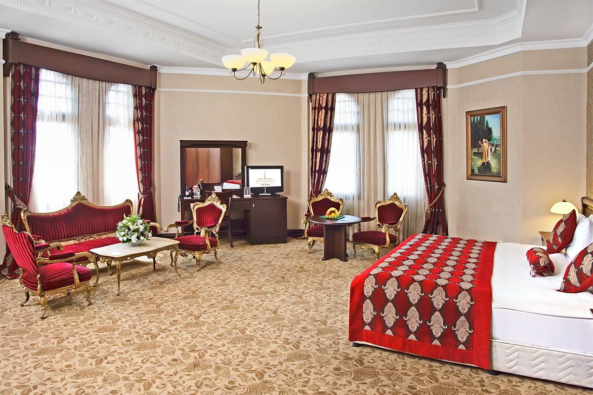 A hotel room with a large bed , couch , chairs , table and mirror.