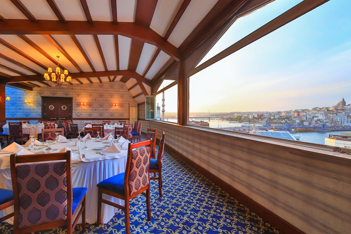 A restaurant with tables and chairs and a view of the water.