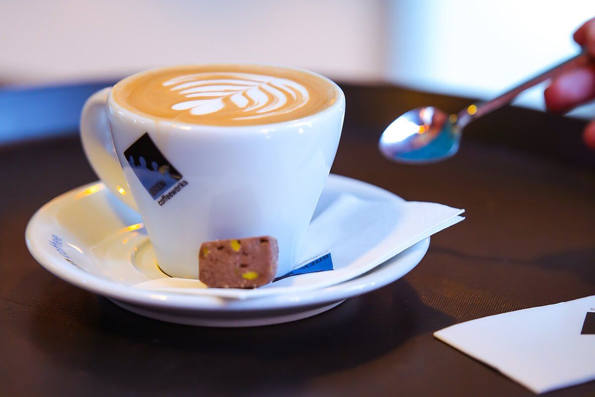 A cup of coffee on a saucer with a spoon