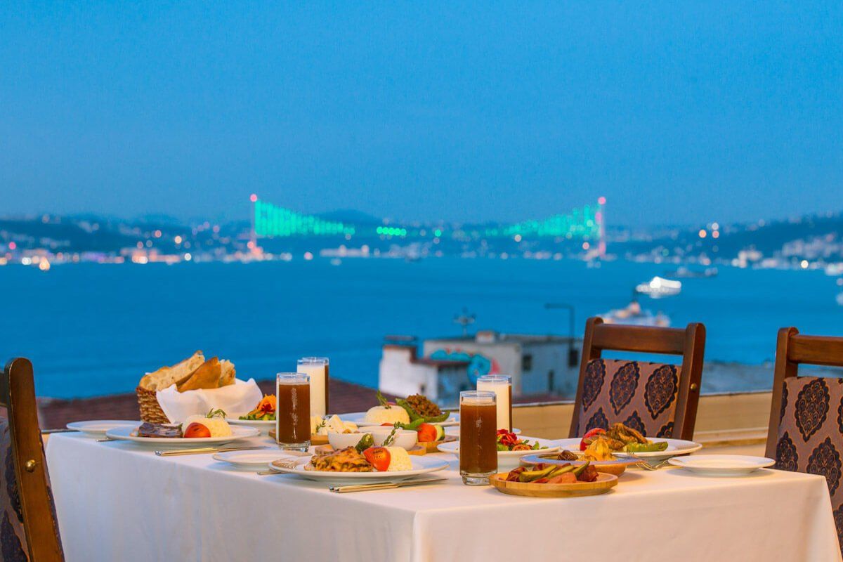 A table with plates of food and drinks on it with a view of the ocean.