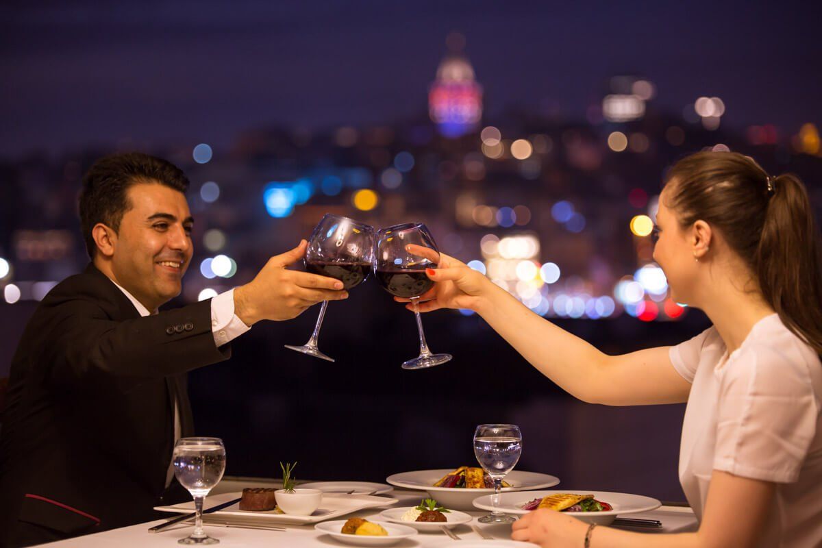 A man and a woman are toasting with wine glasses at a restaurant.