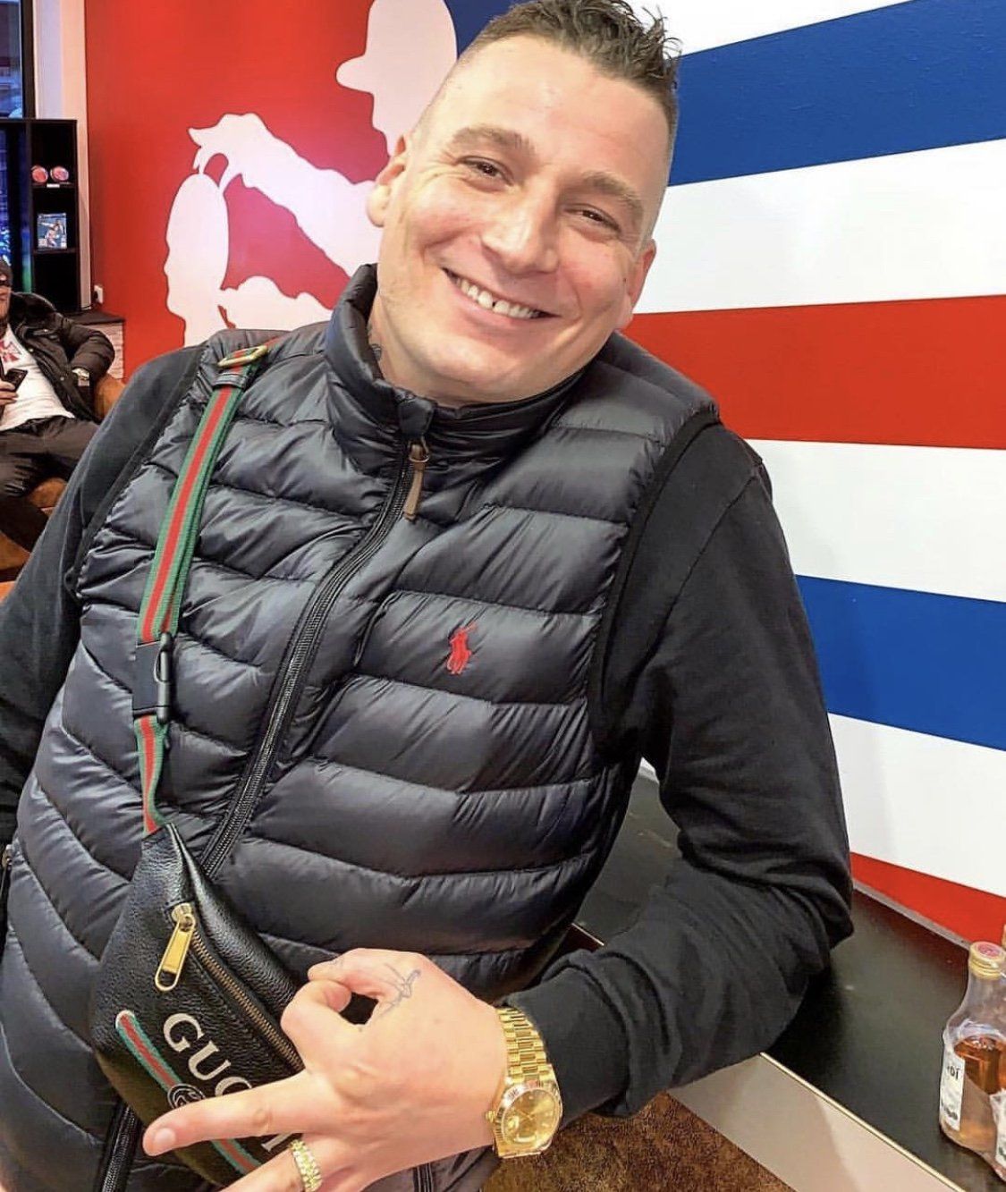 Ein Mann, der eine schwarze Weste mit dem Wort Gucci darauf trägt