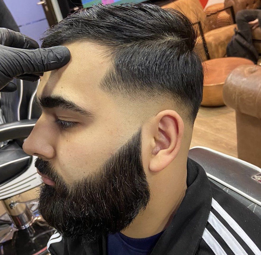 Ein Mann mit Bart lässt sich die Haare schneiden