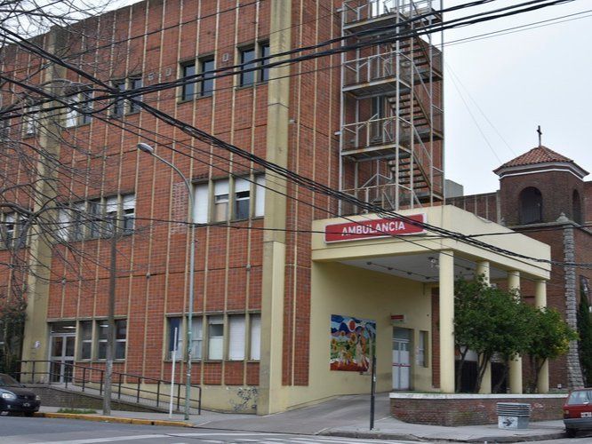 Edificio de ladrillo con un letrero rojo, entrada cubierta y andamios metálicos en el lado izquierdo.