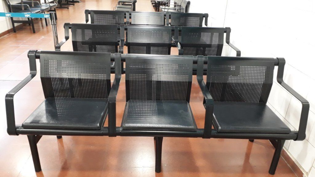 Bancos de metal negro con reposabrazos dispuestos en filas sobre un suelo interior pulido.