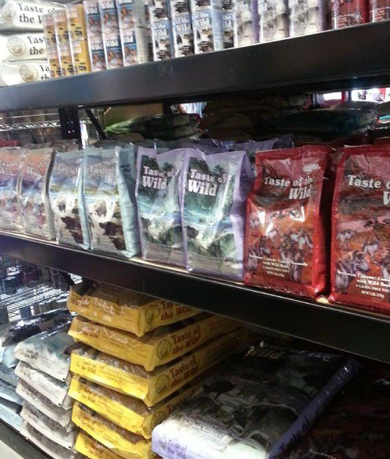 Pet store shelf stocked with colorful bags of animal food and treats.