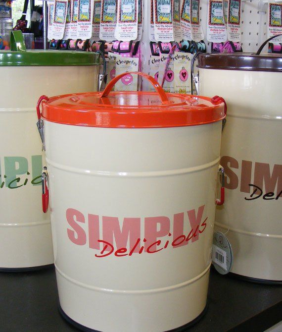 White canister with orange lid labeled “SIMPLY Delicious” on a store shelf with similar containers.