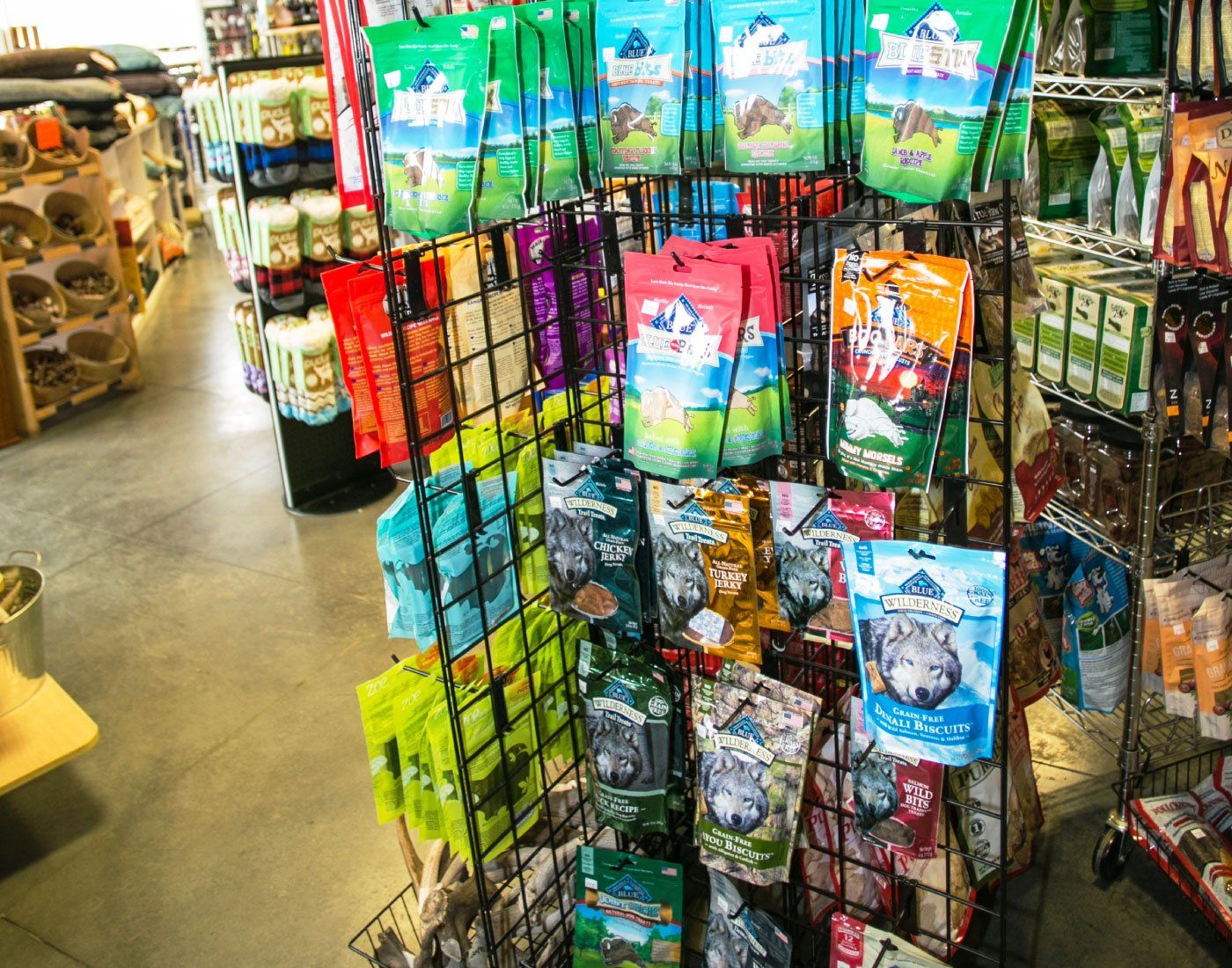 Retail display rack filled with colorful hanging pet treat or toy packages in a store aisle