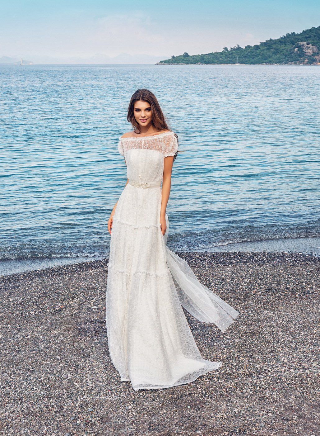 Eine Frau in einem weißen Kleid steht an einem Strand in der Nähe des Meeres.