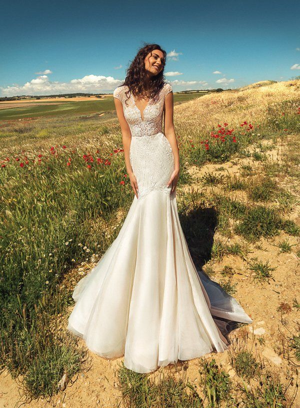 Eine Frau in einem Brautkleid steht auf einem Feld.