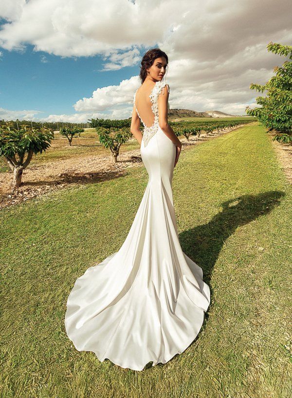 Eine Frau in einem weißen Brautkleid steht im Gras.