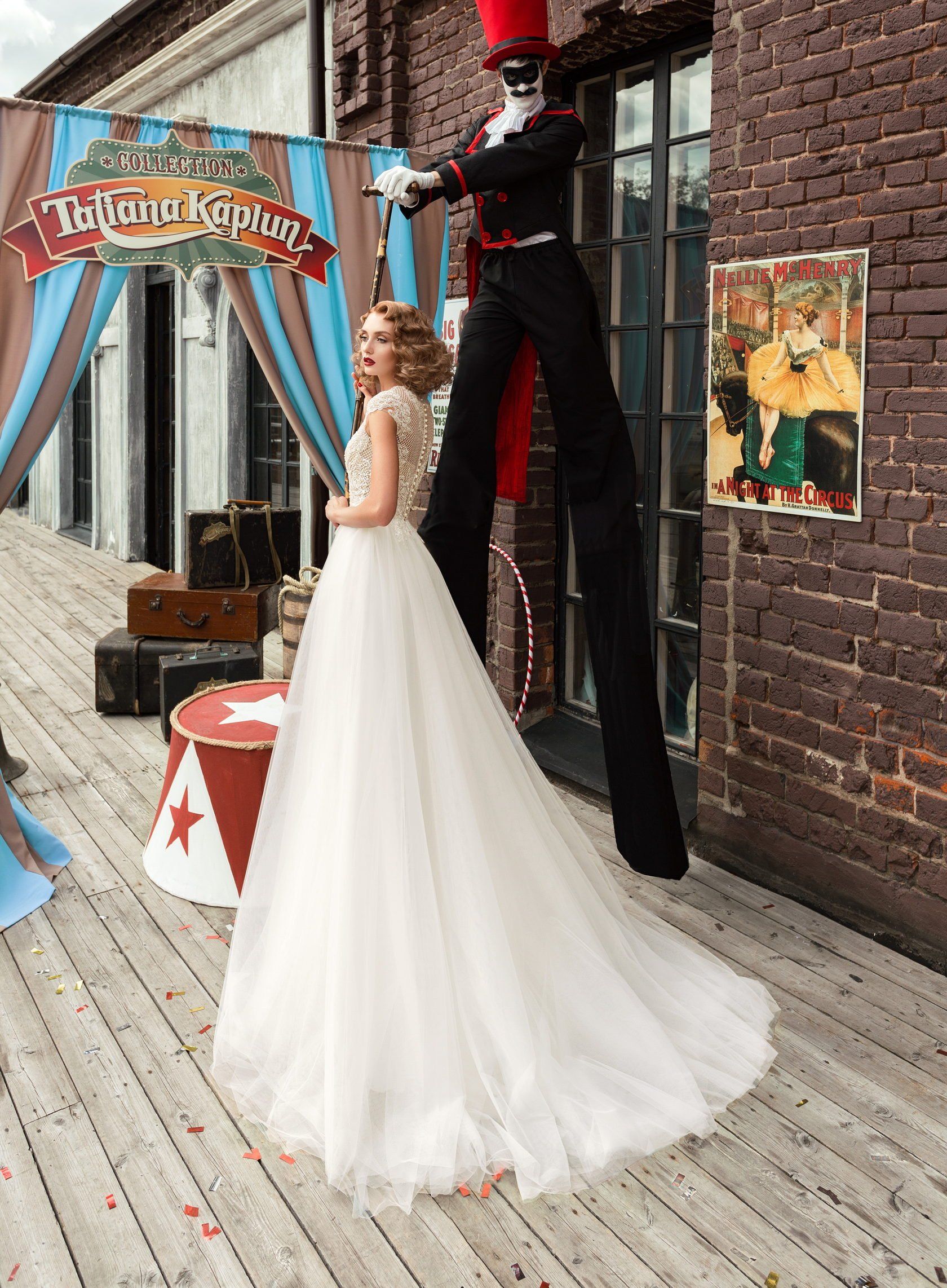 Eine Braut im Brautkleid steht neben einem Mann auf Stelzen.