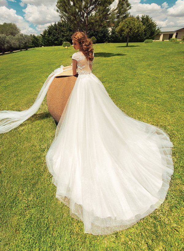 Eine Frau in einem weißen Brautkleid steht auf einer Wiese.