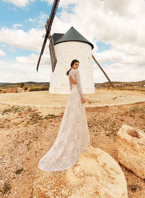 Eine Frau in einem Brautkleid steht vor einer Windmühle.