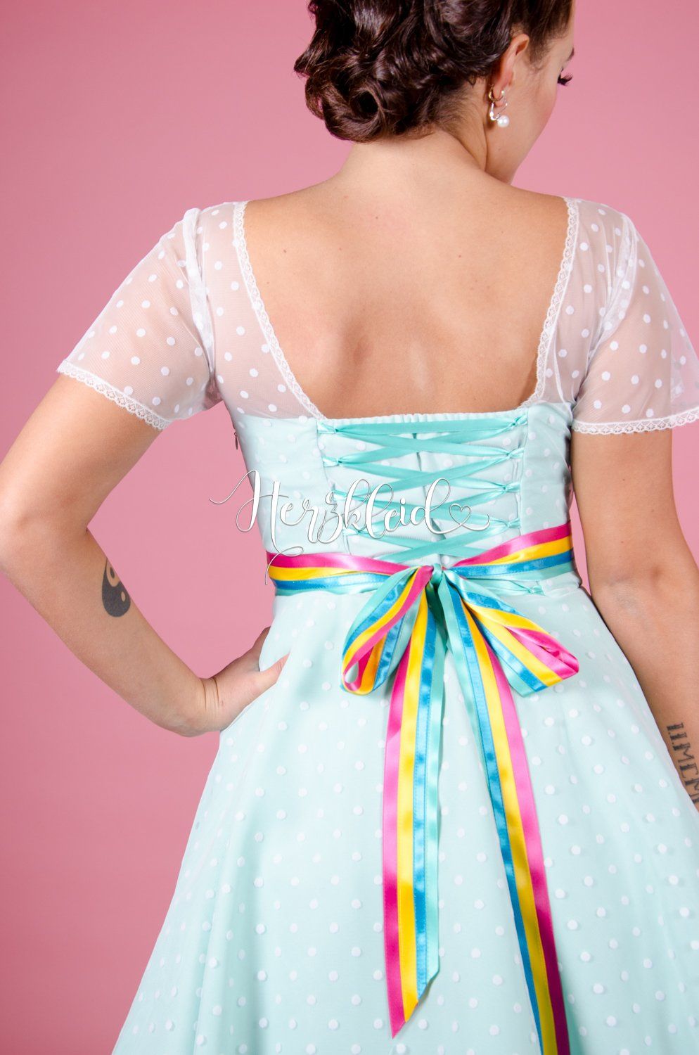 Eine Frau trägt ein blaues Kleid mit einem Regenbogenband um die Taille.