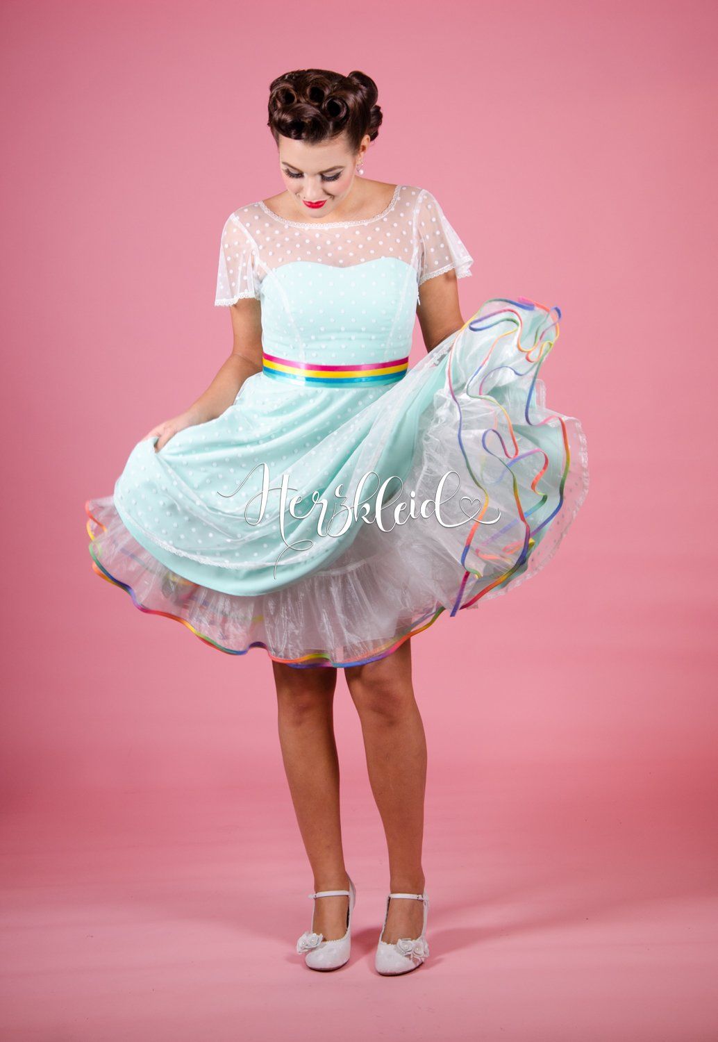 Eine Frau trägt ein hellblaues Kleid mit einem Regenbogenband um die Taille.