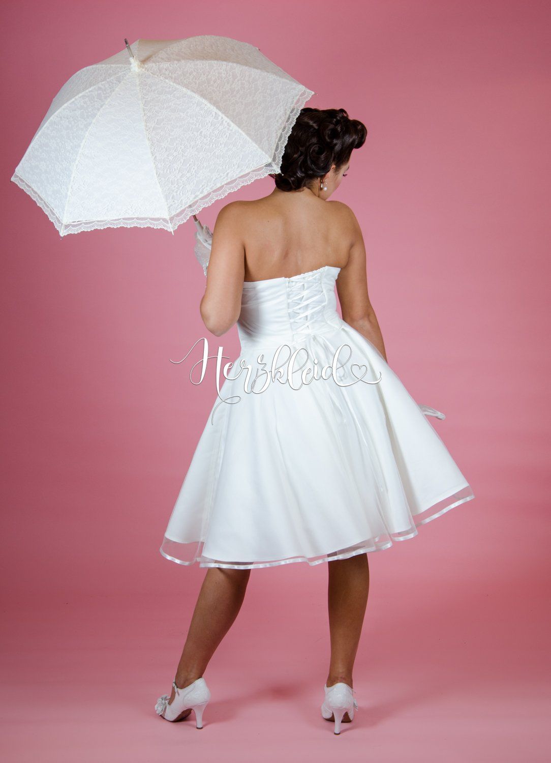 Eine Frau in einem weißen Kleid hält einen Regenschirm