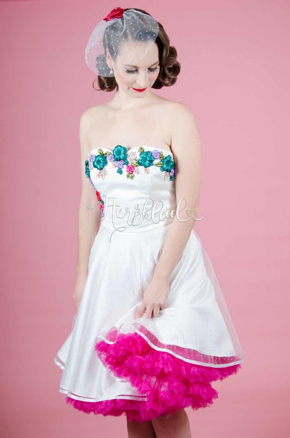 Eine Frau trägt ein weißes Kleid mit rosa Besatz und einen rosa Unterrock.