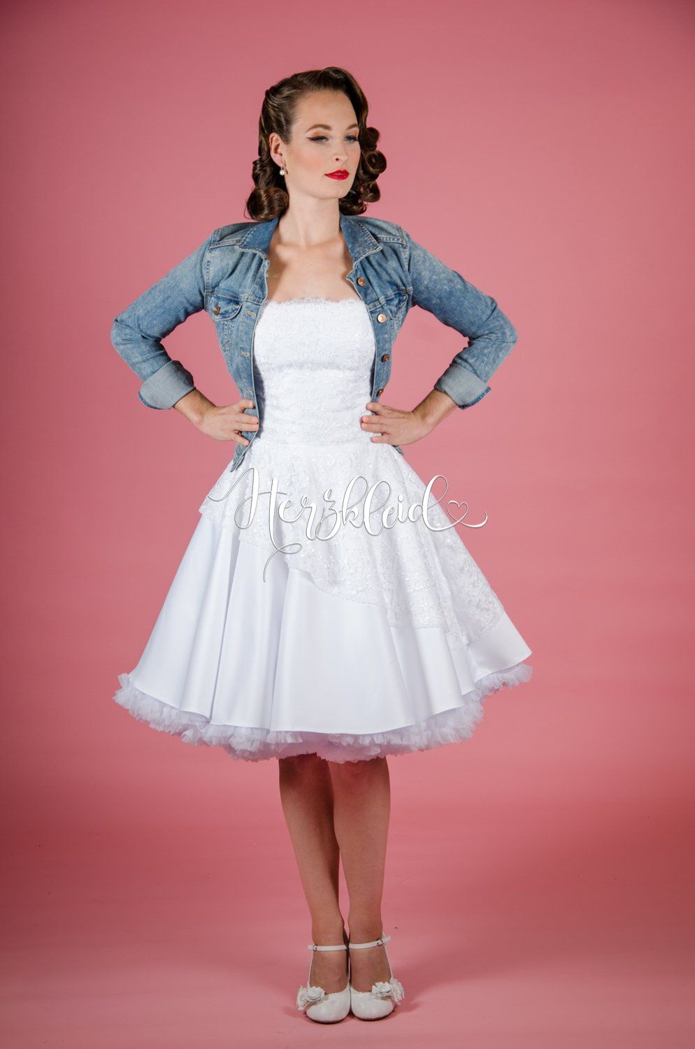 Eine Frau trägt ein weißes Kleid und eine Jeansjacke.