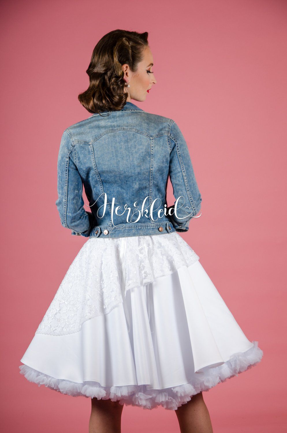 Eine Frau trägt einen weißen Unterrock und eine Jeansjacke.