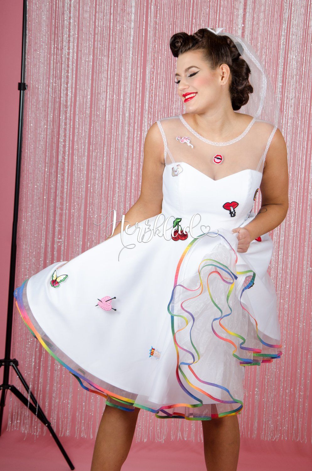 Eine Frau trägt ein weißes Kleid mit einem Regenbogenrock.