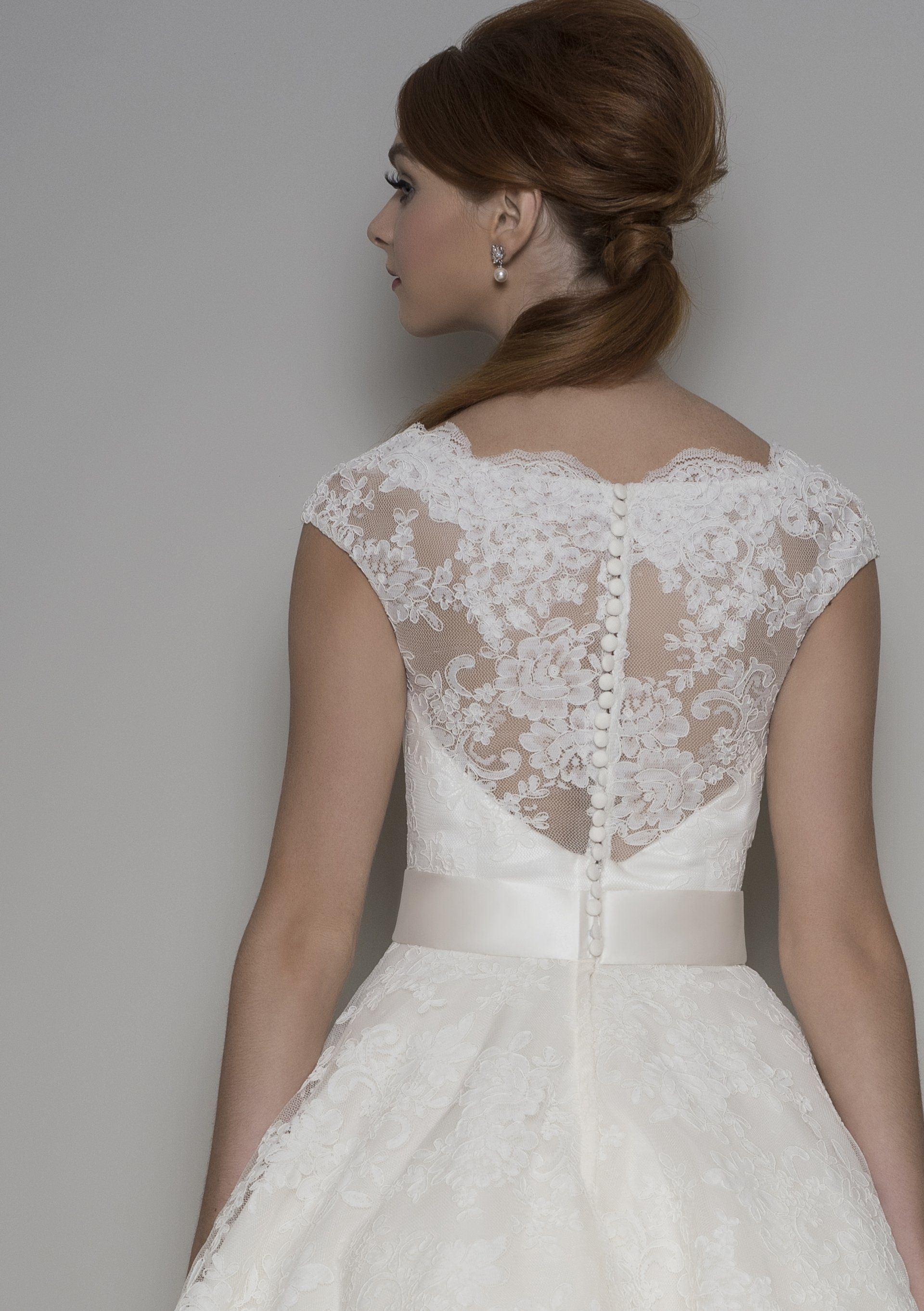 Der Rücken einer Frau, die ein weißes Spitzenbrautkleid trägt