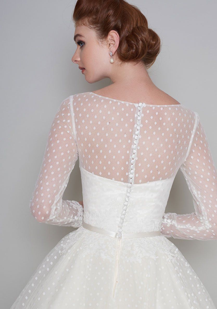 Der Rücken einer Frau, die ein weißes Kleid mit Punkten an den Ärmeln trägt.
