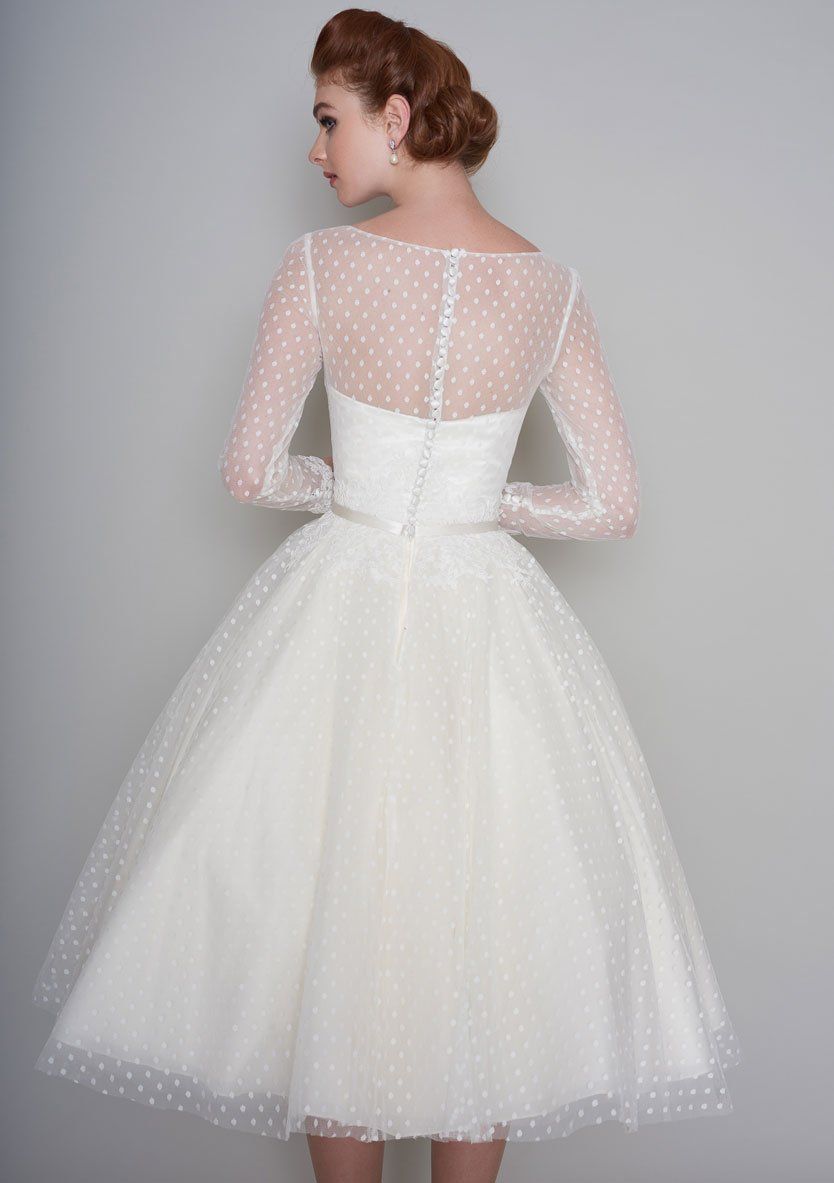 Der Rücken einer Frau, die ein weißes Kleid mit langen Ärmeln und Punkten trägt.