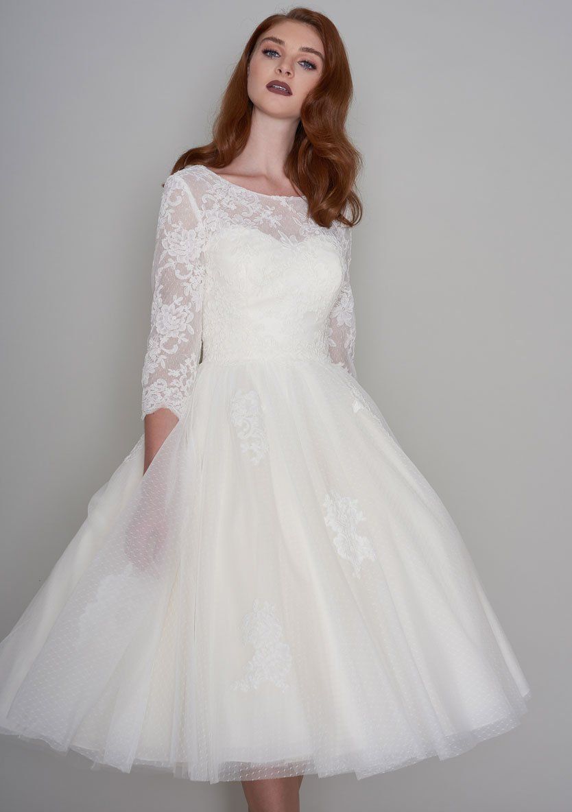 Eine Frau trägt ein weißes Brautkleid mit langen Ärmeln.