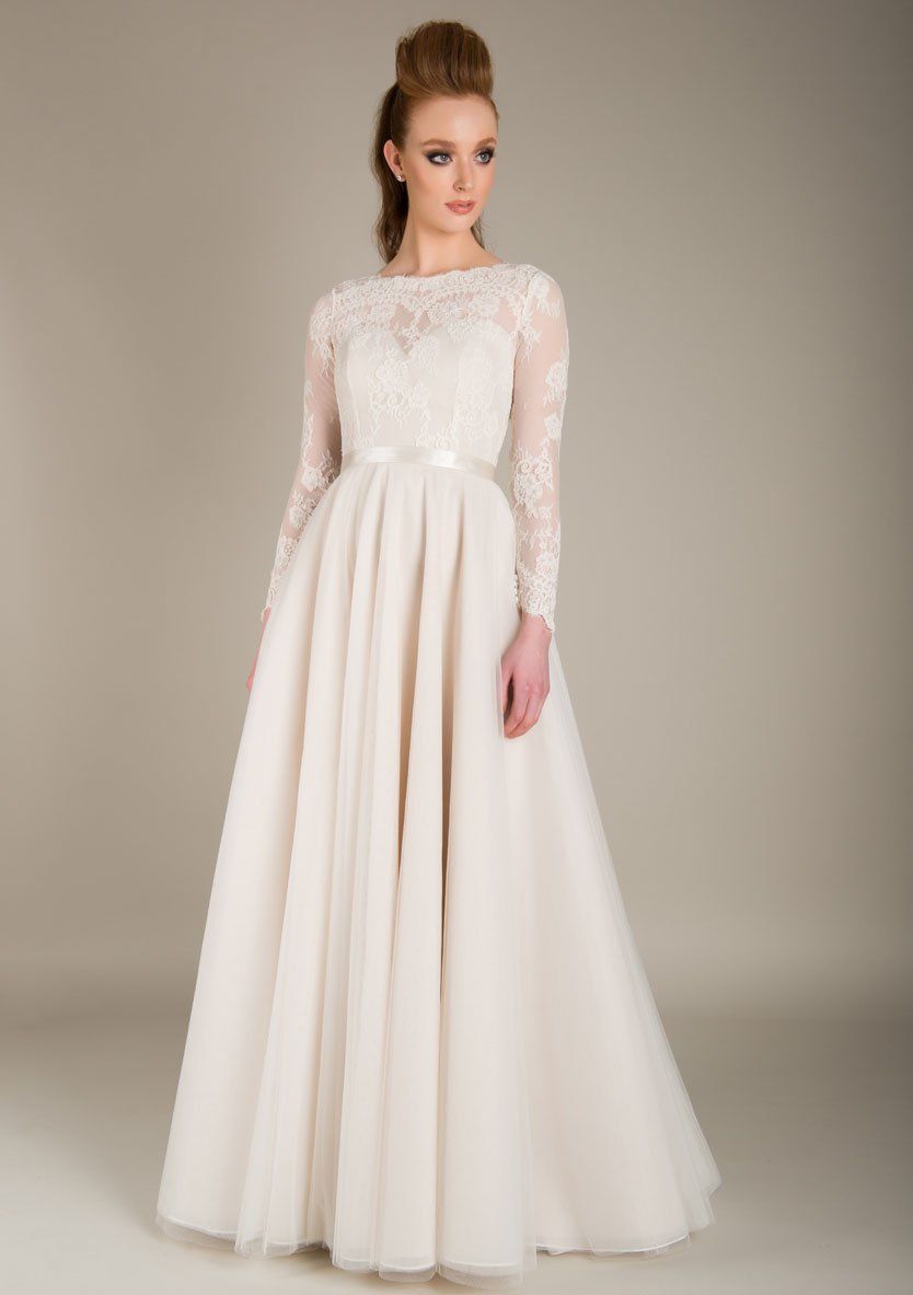 Eine Frau trägt ein weißes Brautkleid mit langen Ärmeln.