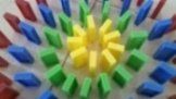 Arrangement of colorful dominoes in a circular pattern, radiating outwards. Yellow in the center, surrounded by green, blue, and red.