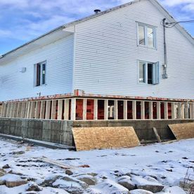 Une grande maison blanche est en construction dans la neige.