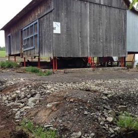 Un grand bâtiment en bois se trouve au sommet d'un chemin de terre.