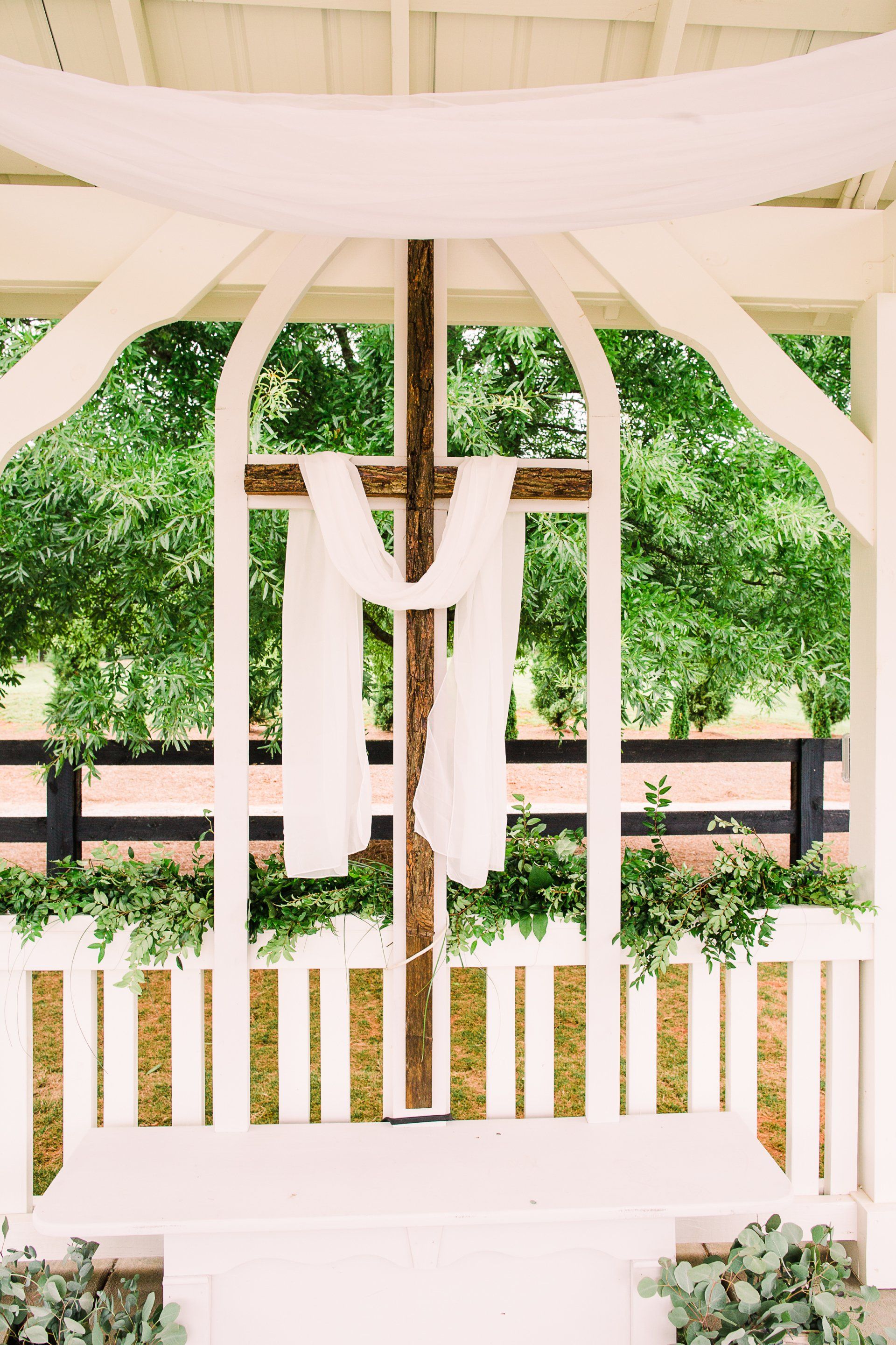 A wooden cross is hanging from the ceiling of a gazebo.