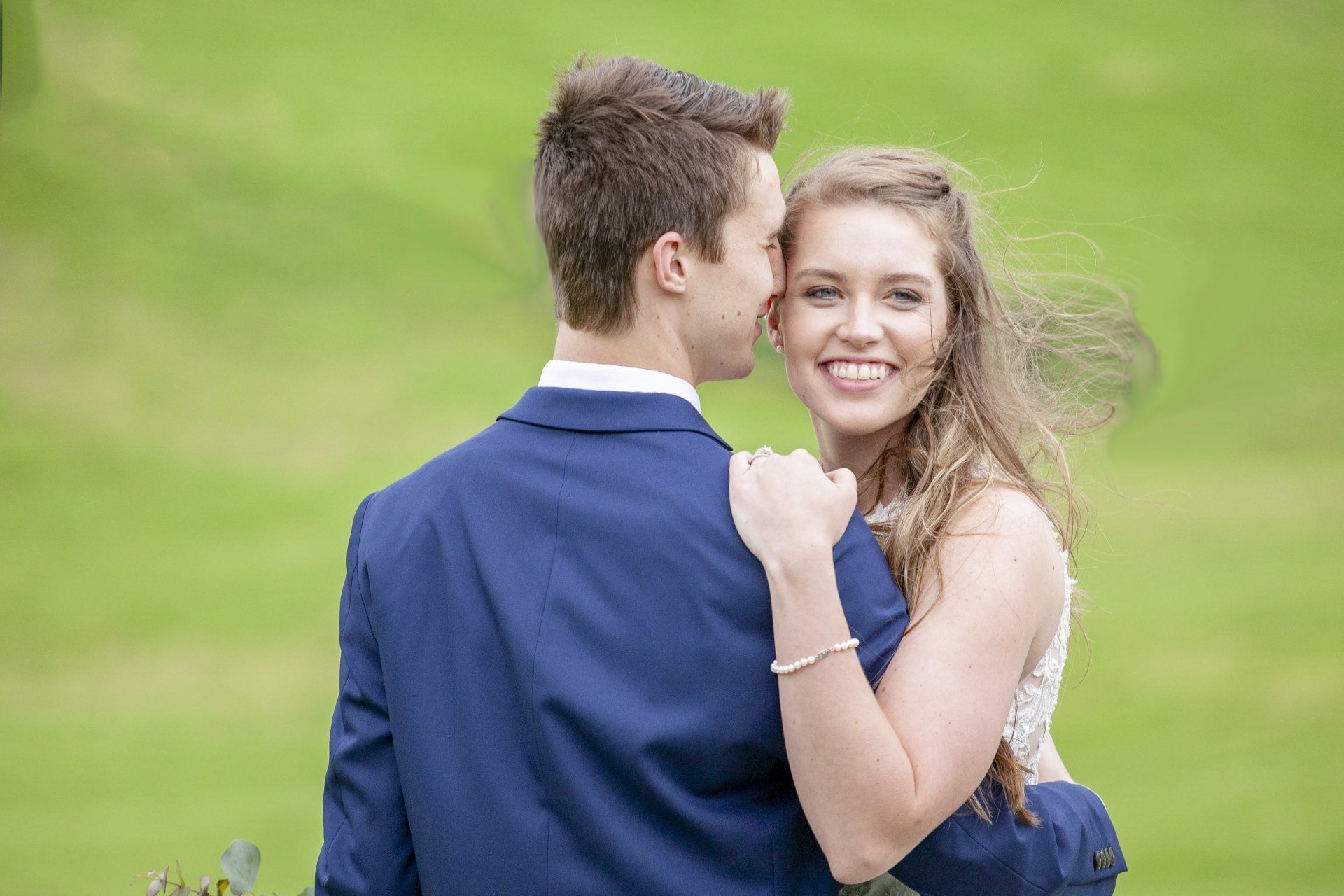 Couple dancing outdoors on a green lawn, smiling with the woman facing the camera.