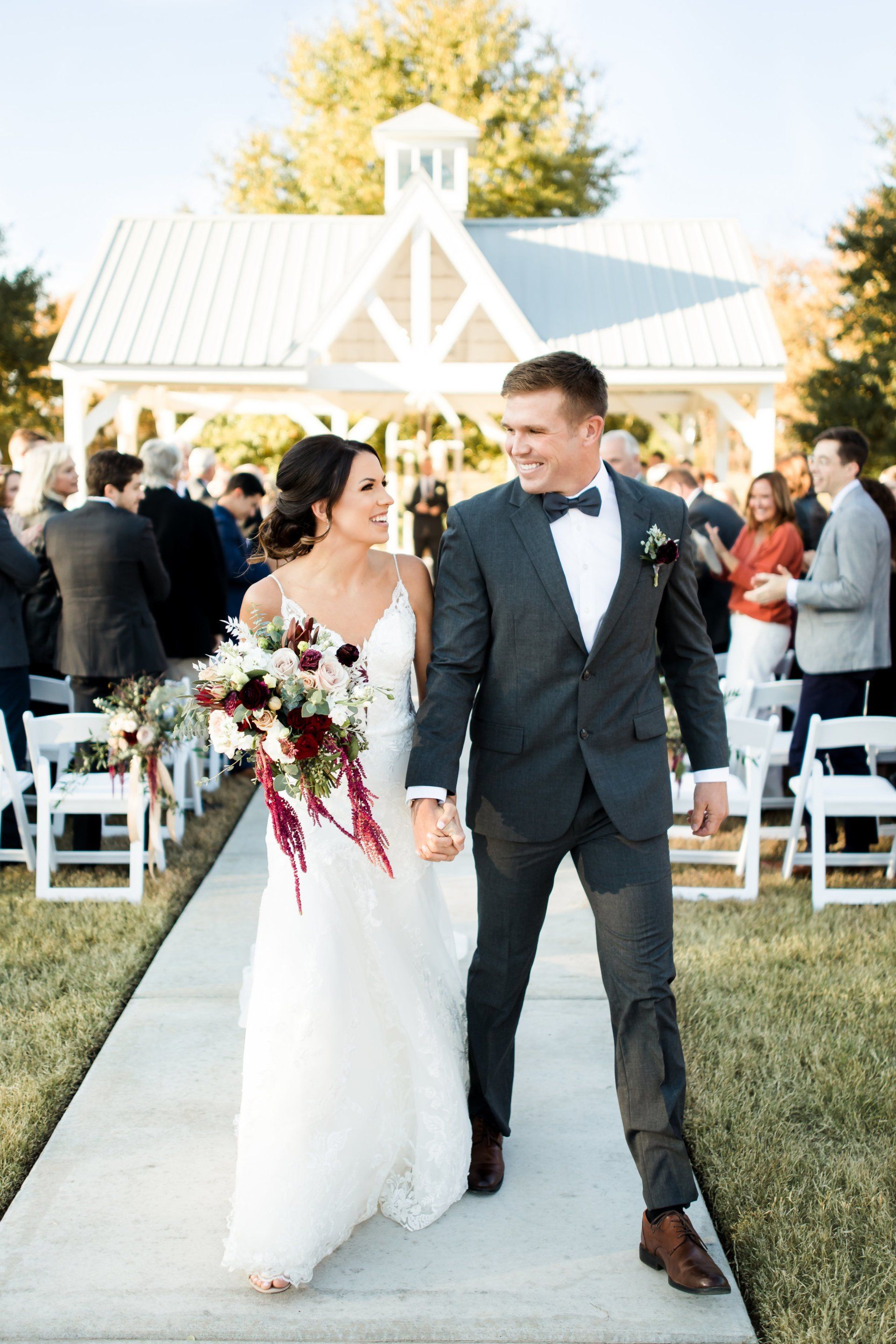 A bride and groom are walking down the aisle at their wedding holding hands.