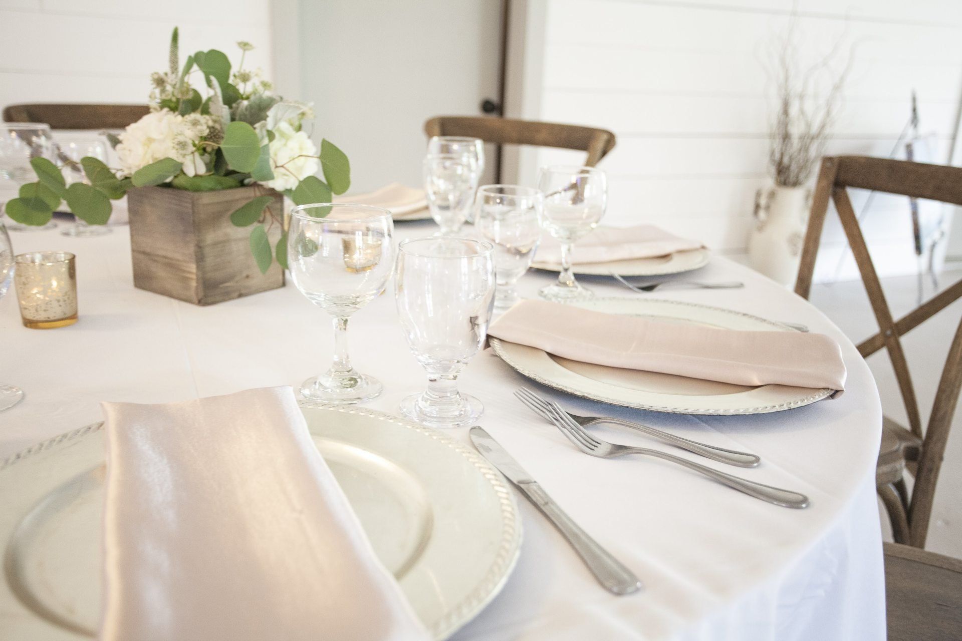 Elegant dining table set with white plates, wine glasses, and a floral centerpiece