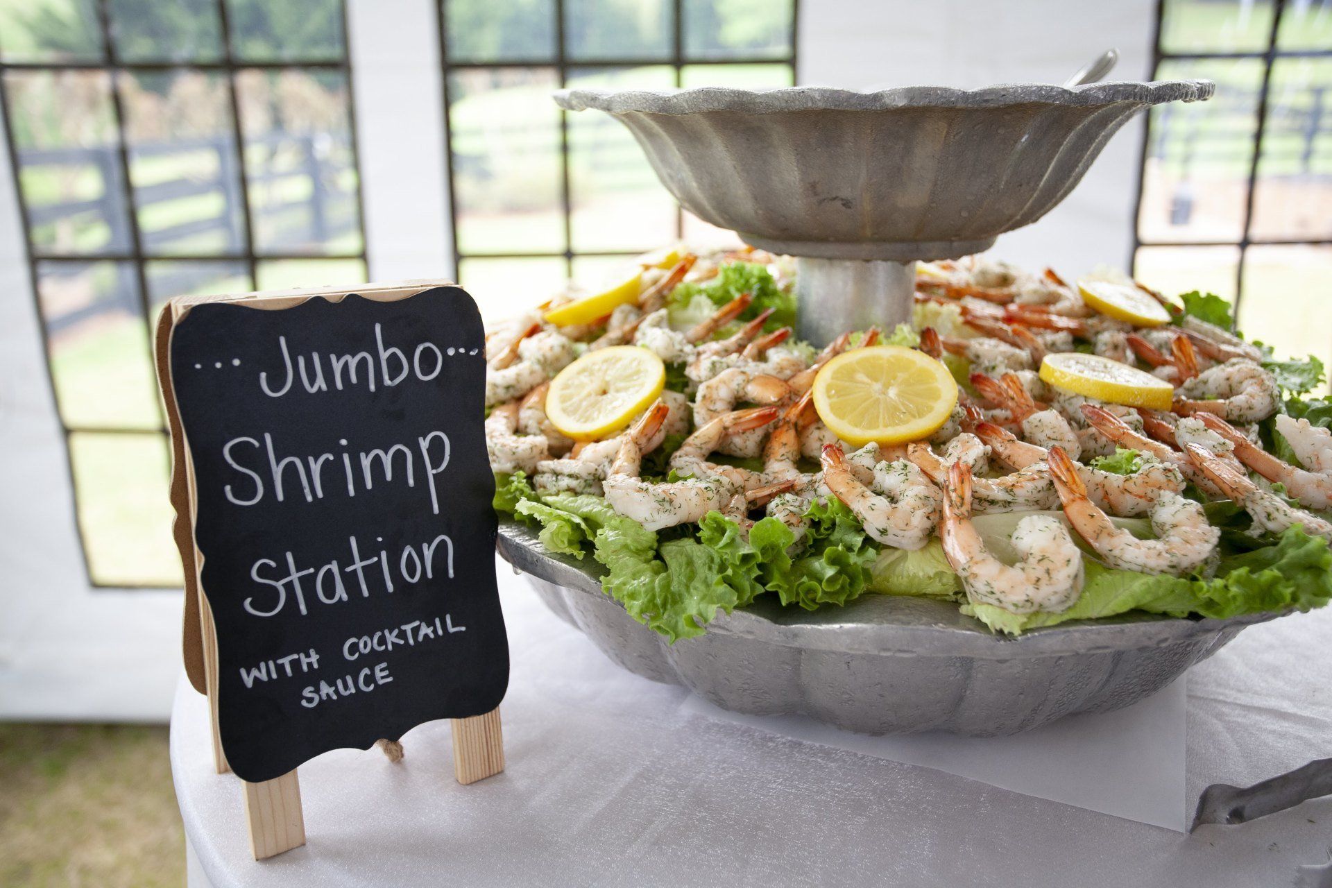Jumbo shrimp station with lemon garnish and a sign, set on a buffet table