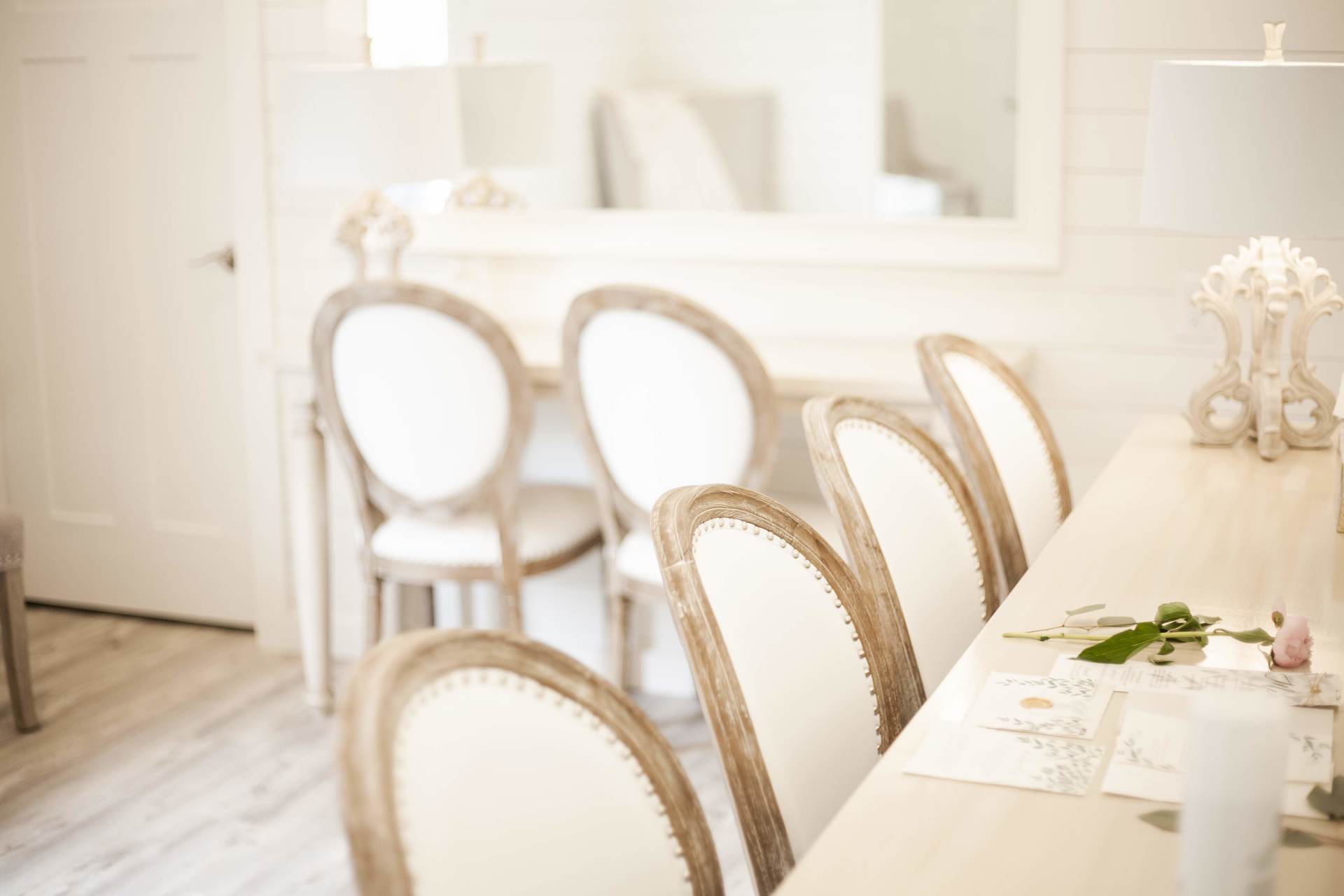 Elegant white dining room with gold-trimmed chairs and a set table in soft natural light