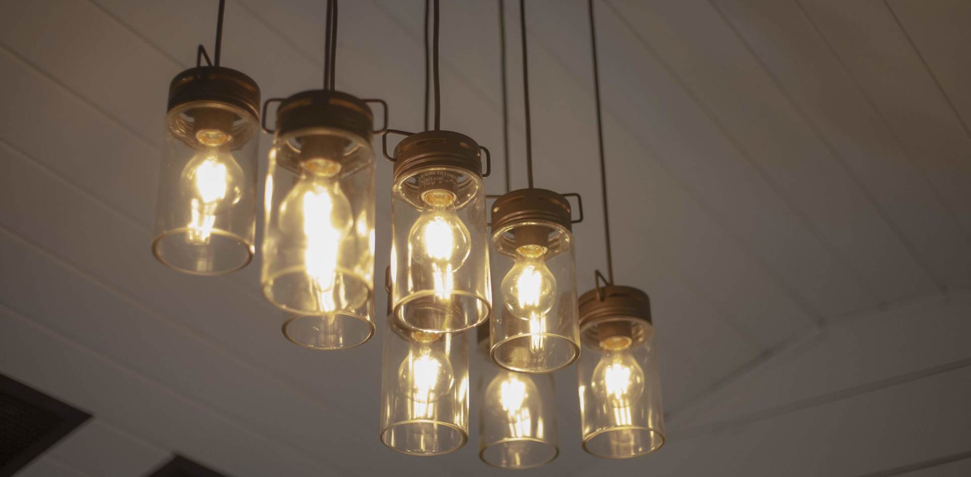 Five glowing industrial-style pendant lights hanging from a ceiling