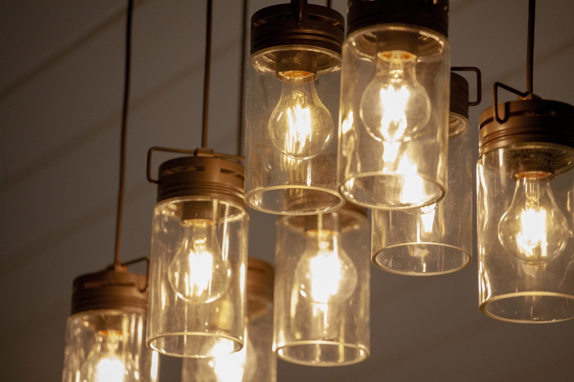 Warm glowing pendant lights in clear glass jars hanging from the ceiling