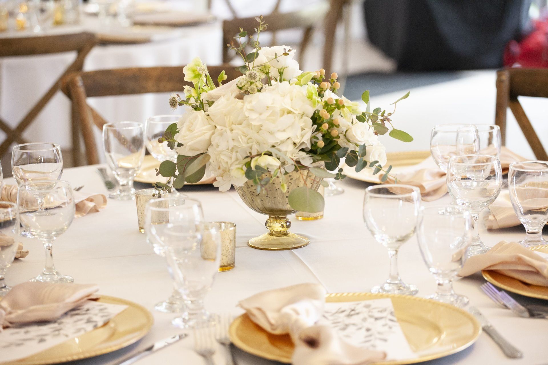 Elegant wedding reception table with white floral centerpiece, gold plates, and glassware