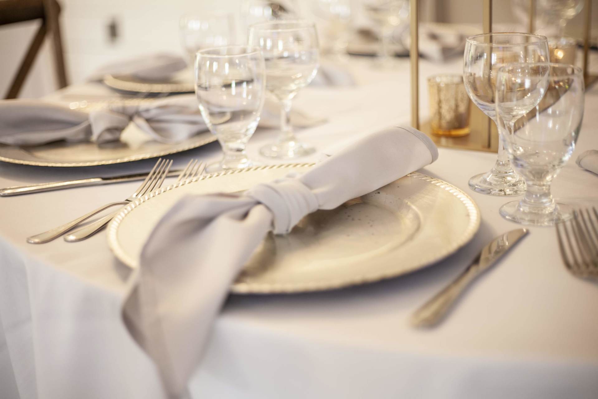 Elegant banquet table with white plates, folded napkins, and wine glasses set for a formal meal