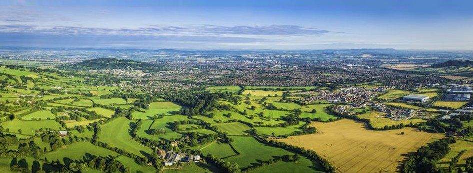 An aerial view of a lush green landscape with a city in the distance.
