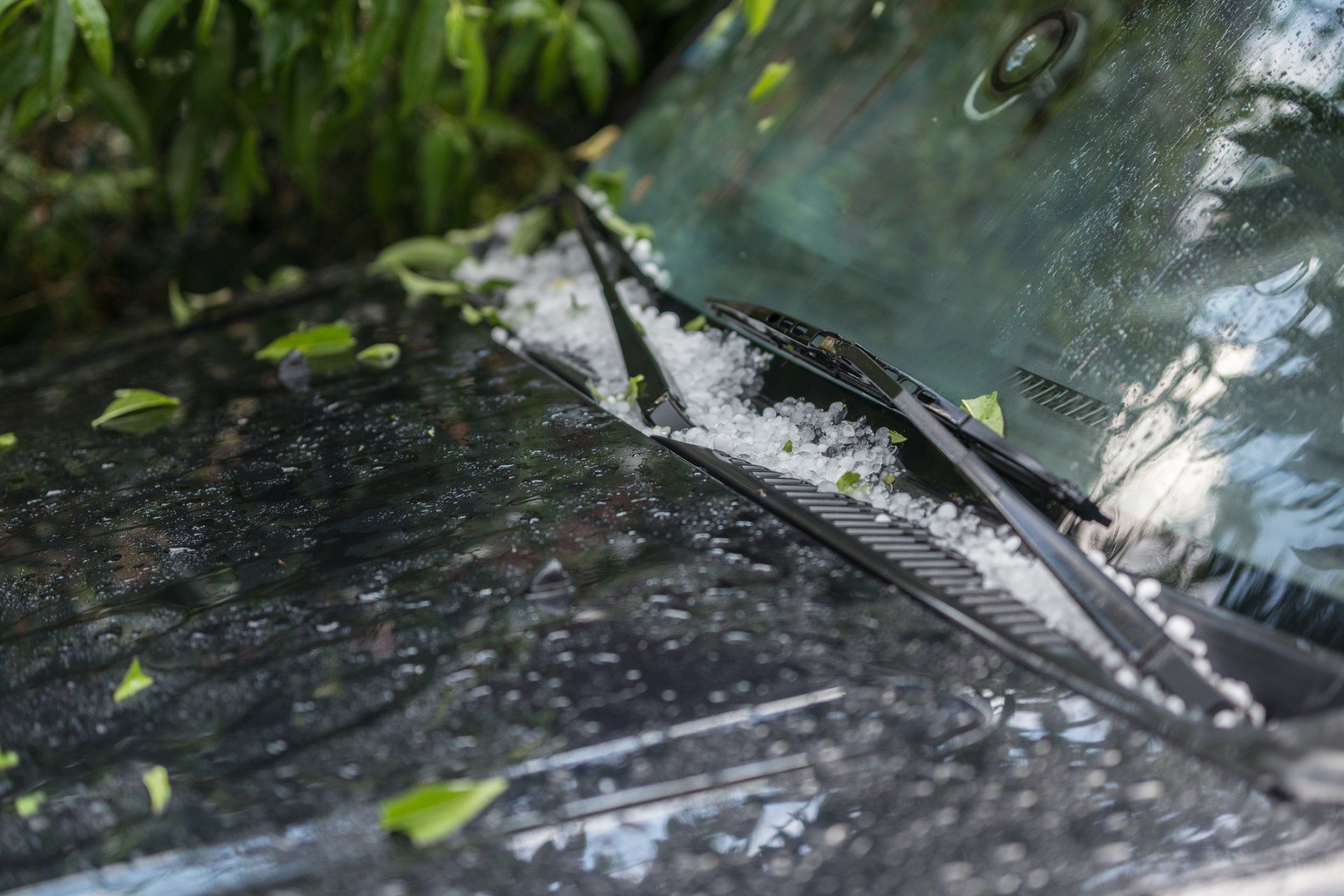 A car with hail on the windshield and wiper blades.
