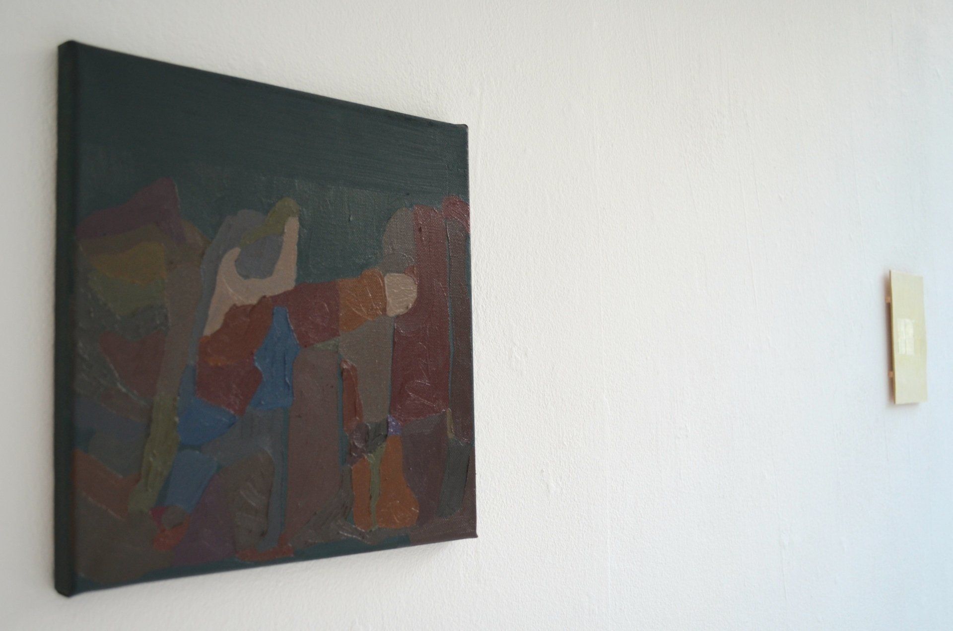 Small abstract landscape painting hanging on white gallery wall